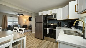 A modern kitchen with white cabinets, stainless steel appliances, and a wooden floor. - 4BR | 4 King Beds | Near Arrowhead | Pets (Blue Springs)