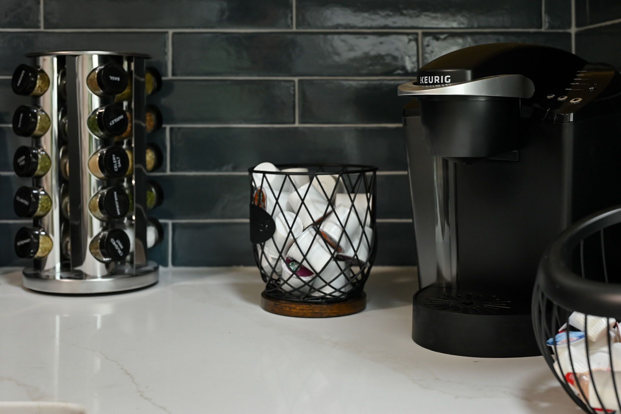 A coffee maker, a spice rack, and a basket of tea bags on a kitchen counter.