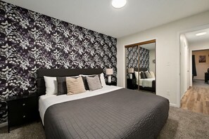 Ein Schlafzimmer mit einem großen Bett, einem Nachttisch, einem Spiegel und einer Wand mit Muster.