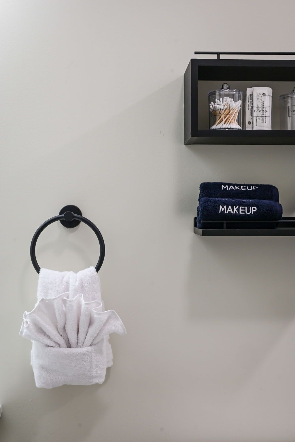 Ein Badezimmer mit Handtuchhalter, Ablagefläche für Toilettenartikel und Handtuchstange.