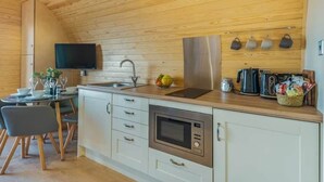 Eine moderne Küche mit Holzboden, weißen Schränken, einer eingebauten Mikrowelle und einer Edelstahl-Spüle.