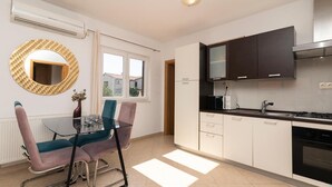Een moderne keuken met een eethoek, een groot raam en een ronde spiegel.