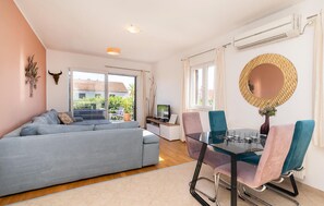 Una sala de estar moderna con un sofá, una mesa de comedor de vidrio con sillas, un televisor y un espejo grande.