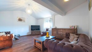 Ein Wohnzimmer mit Sofa, Couchtisch, Fernseher und Schrank.