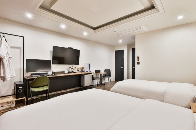 Une chambre d’hôtel comprenant un lit, un bureau avec un ordinateur, une télévision et une chaise.