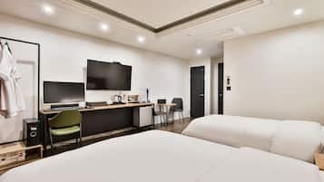 Une chambre d’hôtel comprenant un lit, un bureau avec un ordinateur, une télévision et une chaise.