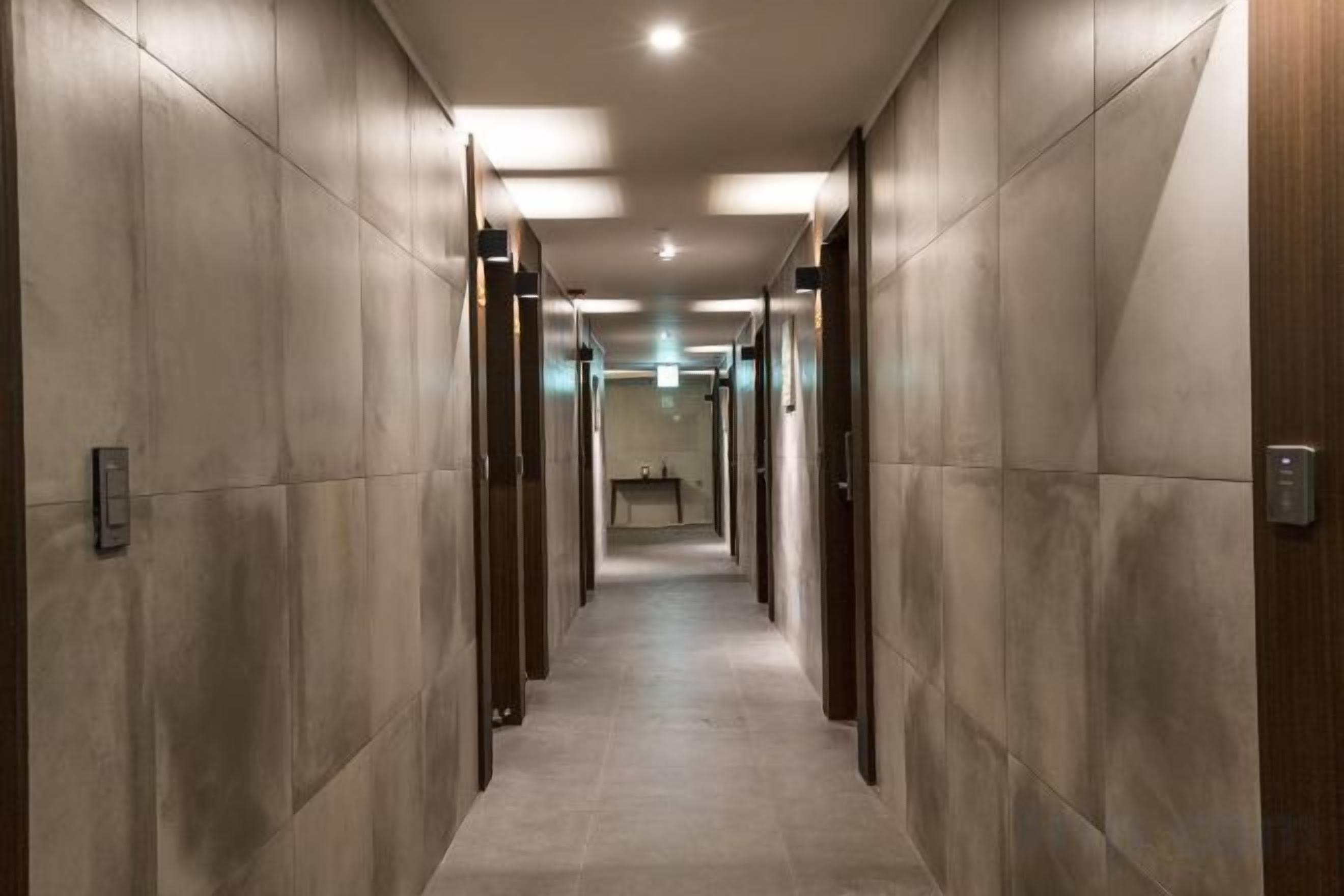 A corridor with doors on both sides, leading to a room at the end.