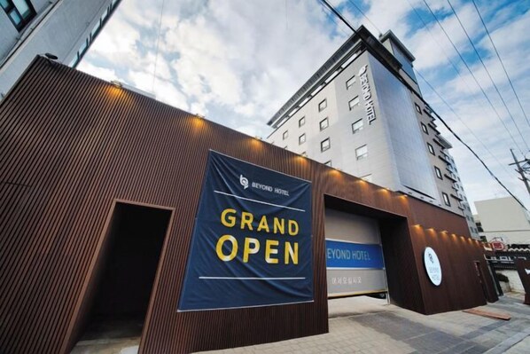 A hotel entrance with a 'Grand Open' banner, a modern facade, and a clear sky. - Beyond Hotel (Incheon)