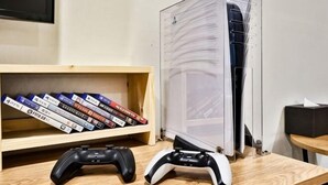 Gamingstation med træhylde, to spillecontrollere og et gennemsigtigt computerkabinet til gaming.