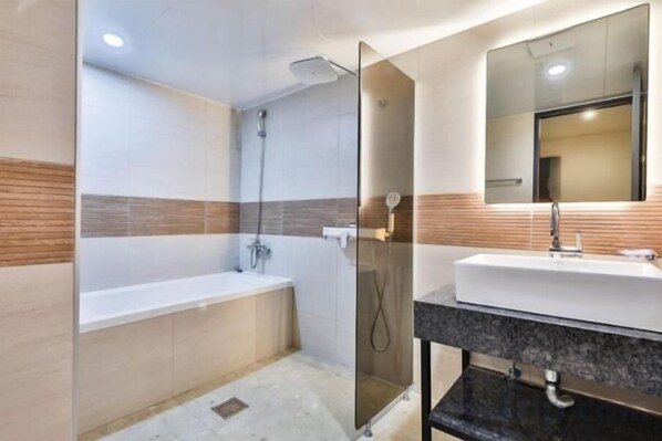 A modern bathroom with a bathtub, a shower, and a vanity with a mirror. - Beyond Hotel (Incheon)