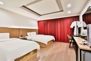 Ein Hotelzimmer mit zwei Betten, einem Schreibtisch, einem Stuhl und einem roten Vorhang.