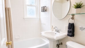 Un baño con bañera, lavabo, inodoro y espejo.