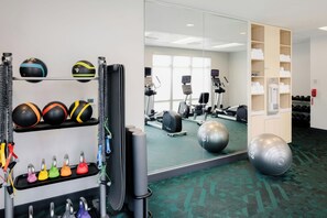 Un gimnasio con equipo de ejercicio, un espejo y un teléfono en la pared.
