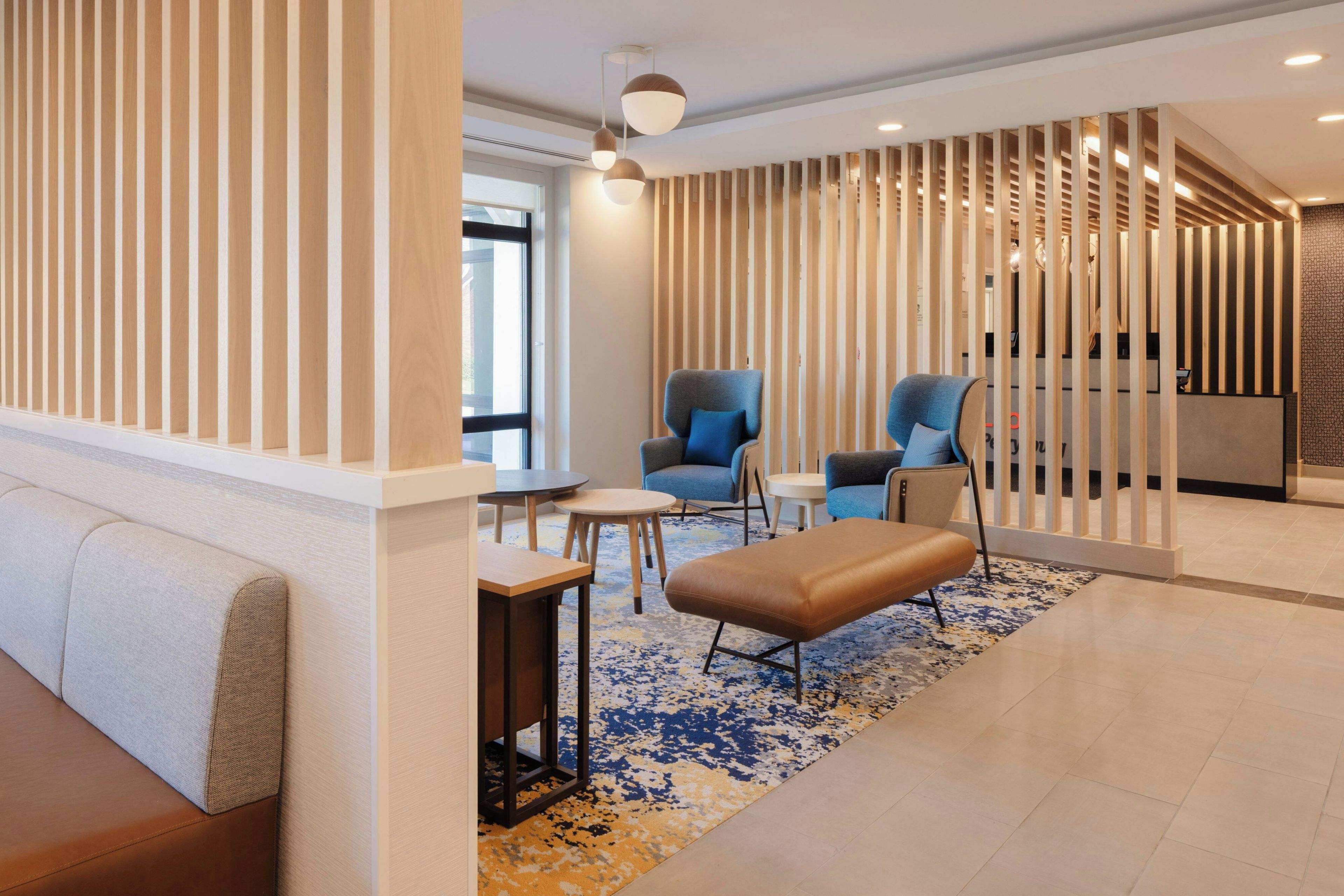 Ein moderner Lounge-Bereich mit Sitzgelegenheiten, einem gemusterten Teppich und einer Holzwand.