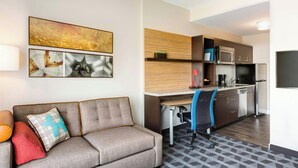Una habitación de hotel moderna con sofá, escritorio y kitchenette.