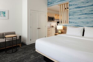 Une chambre d’hôtel comprenant un lit, un coin salon, une kitchenette et une salle de bain.