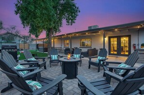 Une terrasse extérieure avec des fauteuils Adirondack, un foyer et un barbecue.