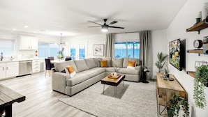 A modern living room with a sectional sofa, a wooden coffee table, and a ceiling fan. - Downtown Gilbert • Hot Tub • Glow Golf • Sleeps 12 (Gilbert)