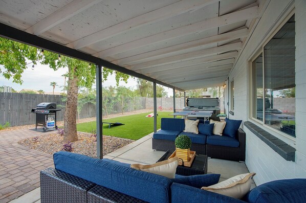 Une terrasse extérieure avec des canapés bleus, une table et un barbecue.