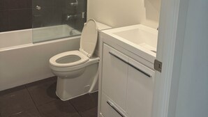 A modern bathroom with a glass-enclosed shower, a white toilet, and a vanity with a mirror.