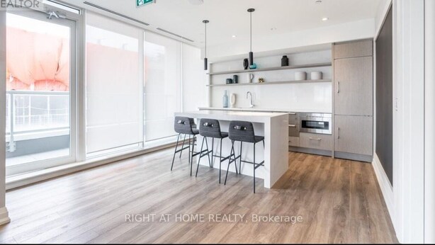 A modern kitchen with a central island, bar stools, and a large window.