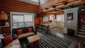 L’intérieur d’une cabane en rondins comprend un espace de vie, une cuisine et un balcon.