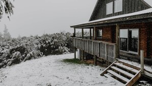 Une cabane en bois dotée d’un porche et d’un escalier menant à l’entrée.