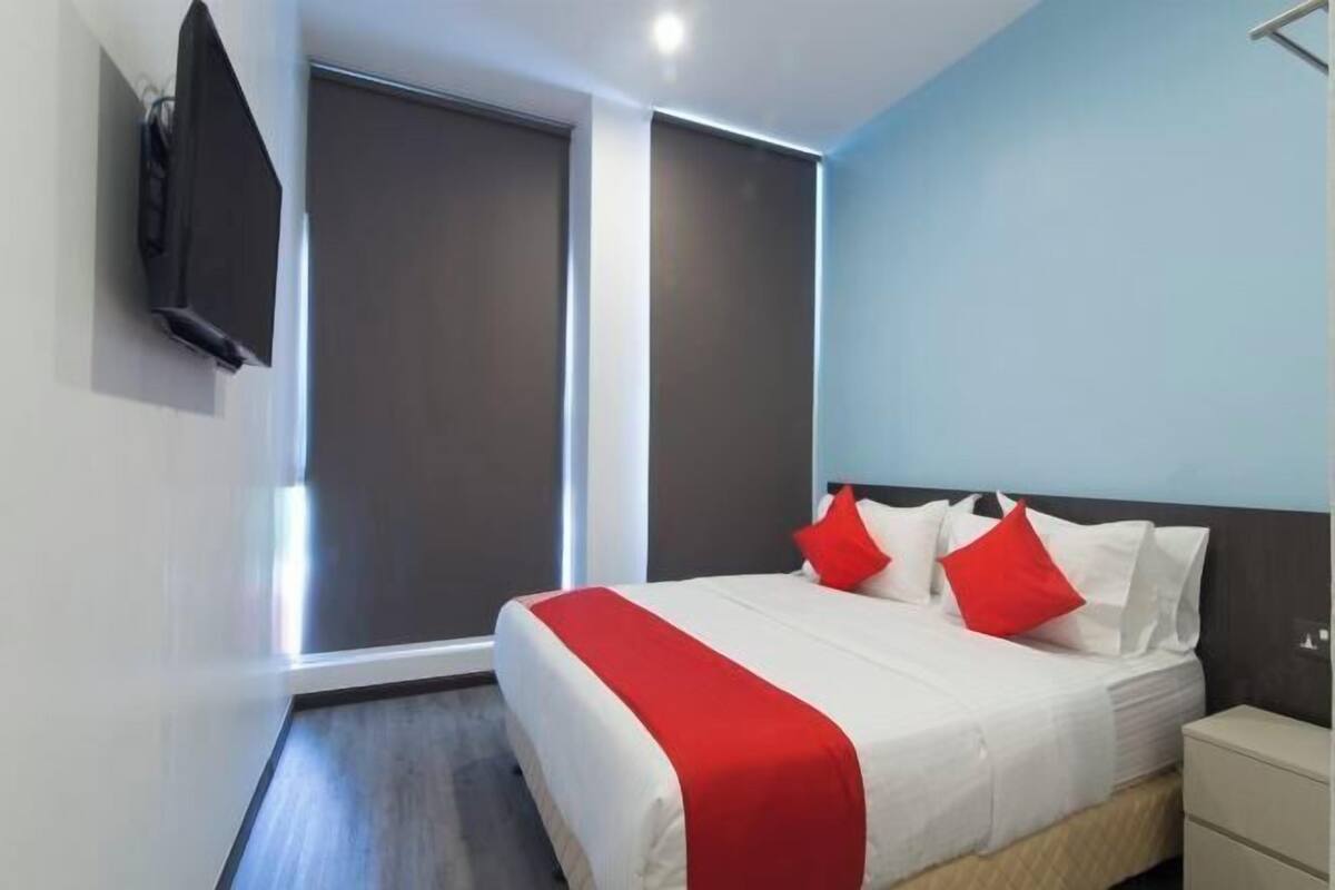 A modern hotel room with a large bed, a nightstand, and a TV mounted on the wall.