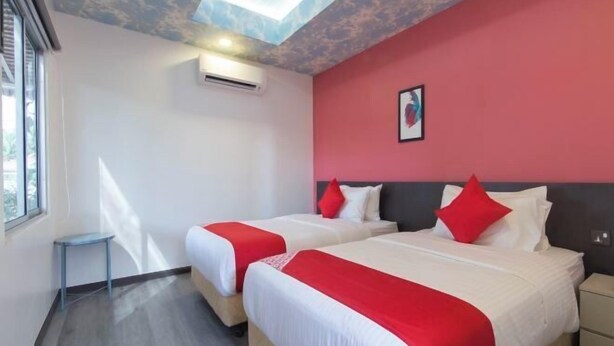 A hotel room with two beds, a skylight, a small table, and a nightstand. - Hotel O Rg Motel (Temin)