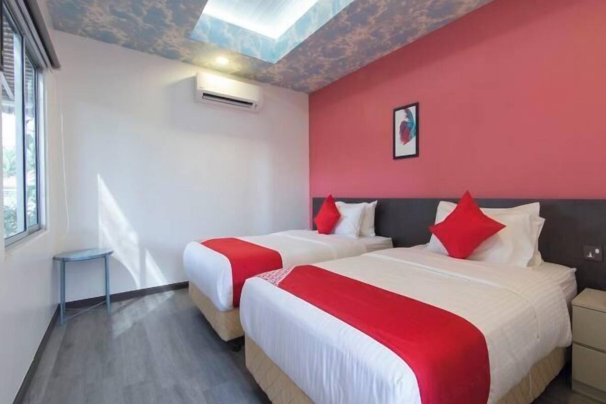A hotel room with two beds, a skylight, a small table, and a nightstand.