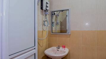 A bathroom with a sink, mirror, and a shower unit.