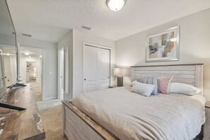 A bedroom with a large bed, a wooden dresser, a mirror, and a painting on the wall. - 5 bdrm Pet friendly, private pool, comm. waterpark (Davenport)