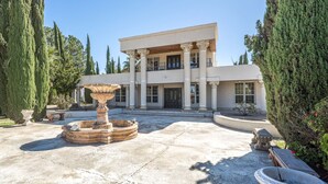Un imposant bâtiment doté d’une cour intérieure, avec une grande fontaine et des colonnes disposées de manière symétrique.