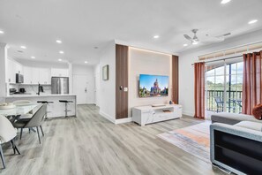 A modern kitchen with white cabinets, a stainless steel refrigerator, and a dining area with a glass table and chairs. - Luxury Stay Near Orlando Theme Parks (Davenport)