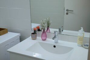 A bathroom with a white sink, a mirror, a glass door, and a small potted plant. - VIVA República Serviced Apartment -1T (Porto)