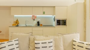 A modern kitchen with white cabinets, a built-in microwave, and a coffee maker. - VIVA República Serviced Apartment -1T (Porto)