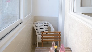 A narrow balcony with a wooden bench and a small table, a potted plant, and two decorative vases. - VIVA República Serviced Apartment 0T (Porto)