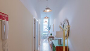 A hallway with a telephone, a mirror, and a table with chairs. - VIVA República Serviced Apartment 0T (Porto)