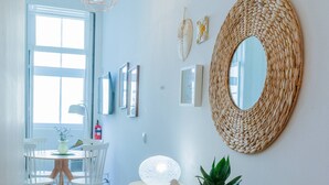 A bright hallway with a wooden floor, a round woven mirror, and a table with chairs. - VIVA República Serviced Apartment 1T (Porto)