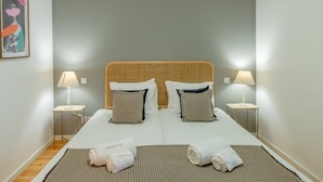 Un letto matrimoniale con due cuscini, un comodino con una lampada e un quadro appeso al muro.