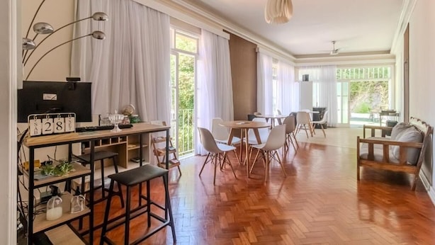 Un vaste espace de vie doté d’un plancher en bois, d’une table à manger avec des chaises, d’un canapé et d’un téléviseur posé sur un meuble.