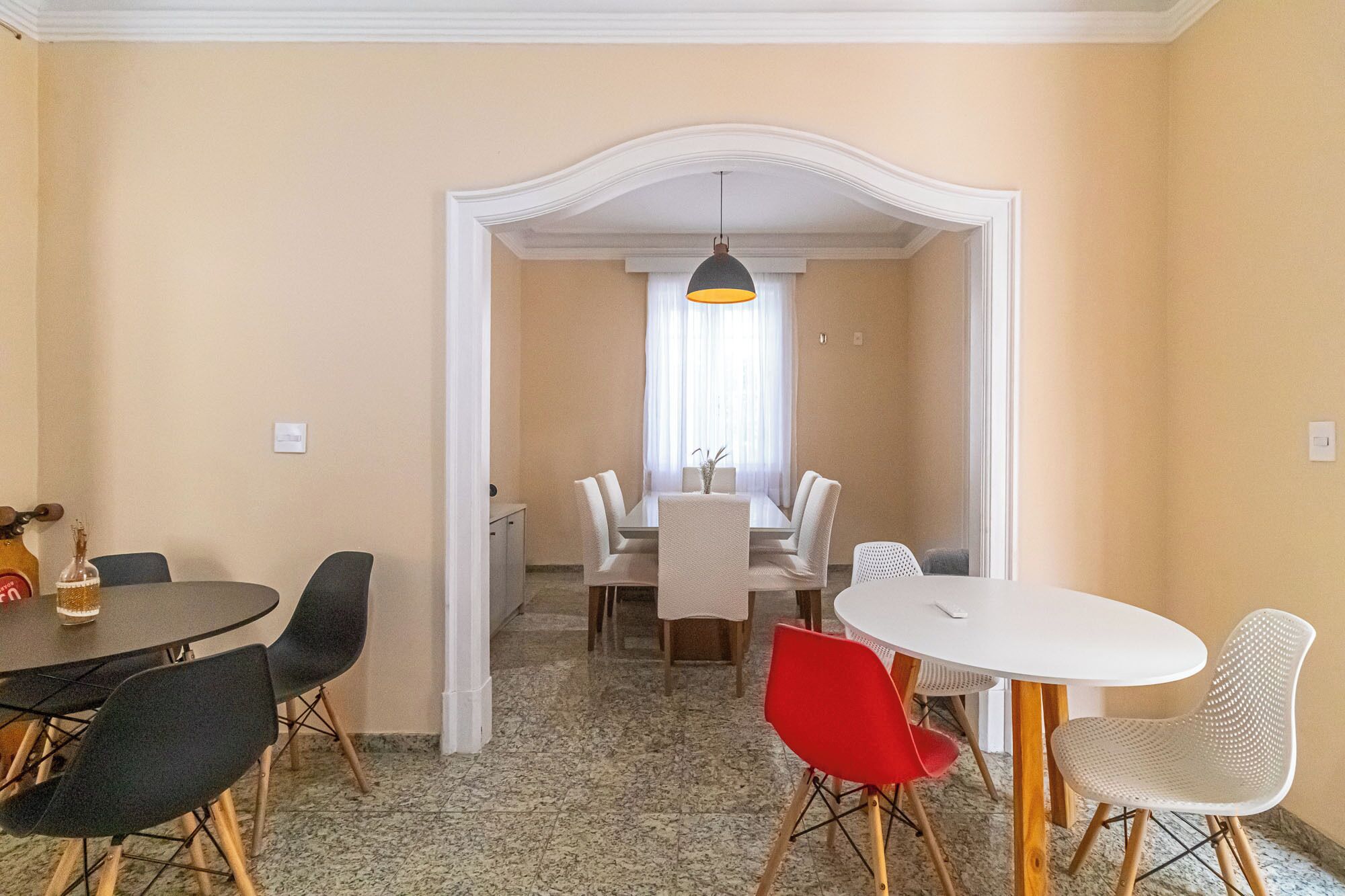 Un comedor con una mesa, sillas, una araña y una ventana con cortinas.