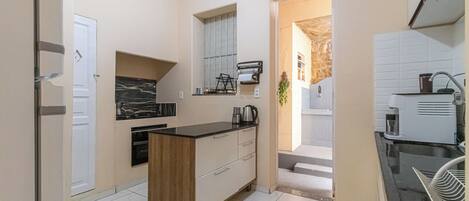 A compact kitchen with a central island, a built-in oven, and a coffee machine.