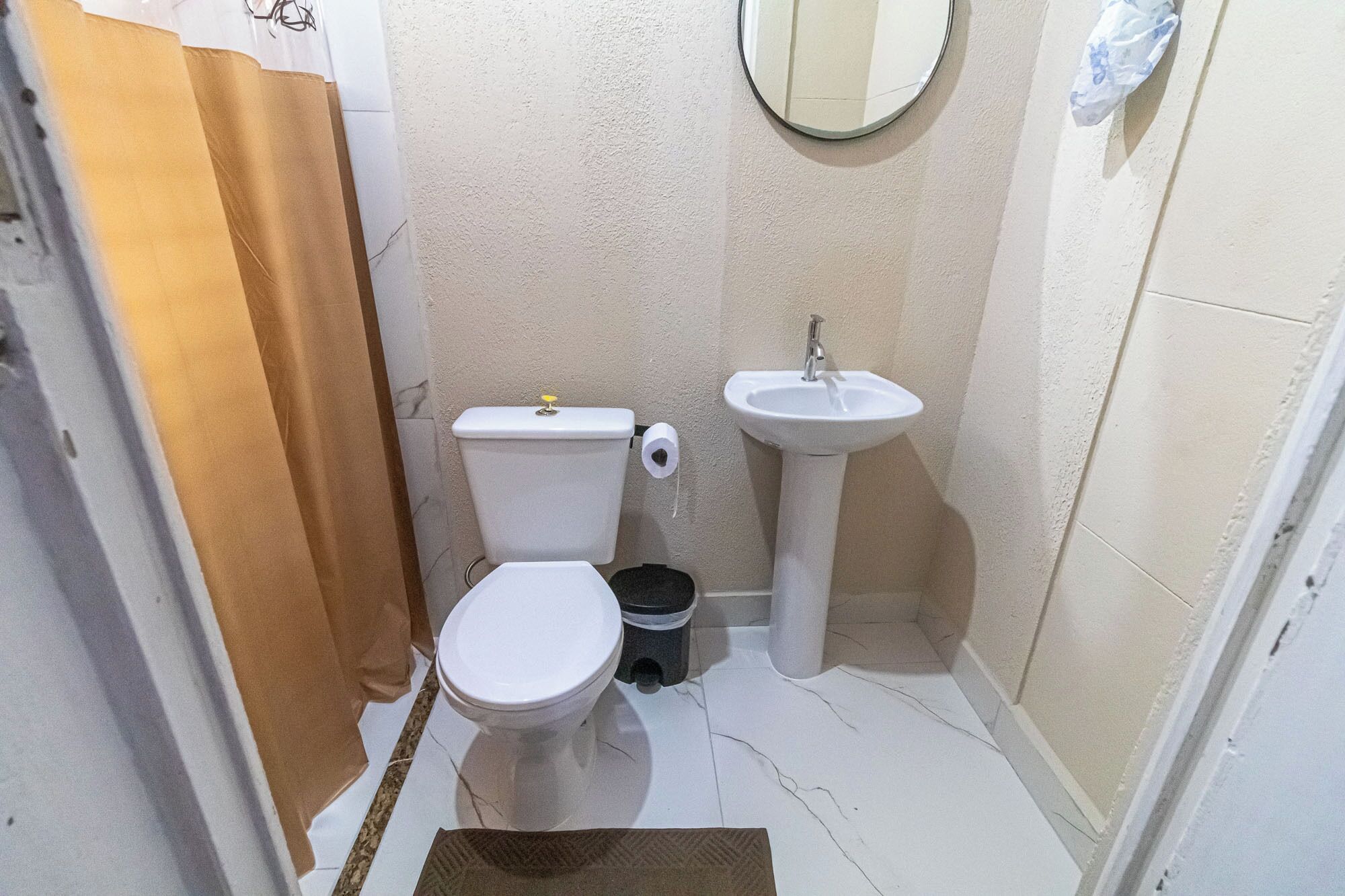 Een compacte badkamer met toilet, wastafel en een spiegel aan de muur.