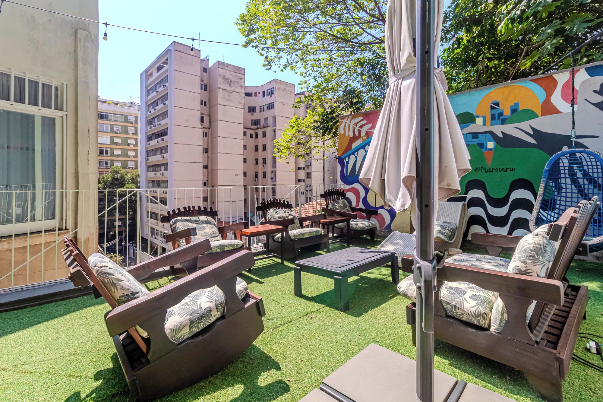 An outdoor seating area with multiple chairs and tables, surrounded by a green artificial turf.