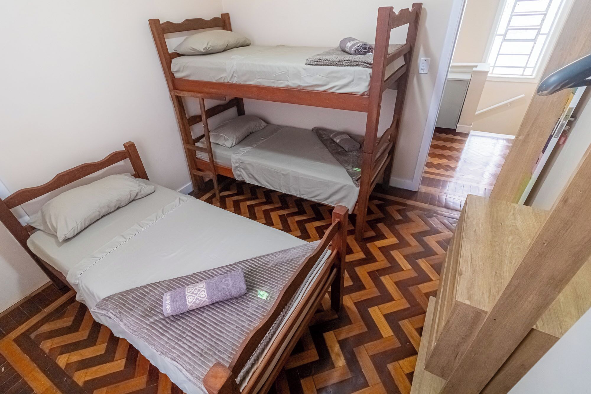 Ein Zimmer mit drei Etagenbetten, Holzboden und einem Fenster.