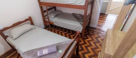 Ein Zimmer mit drei Etagenbetten, Holzboden und einem Fenster.