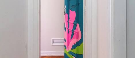 Un couloir doté d’un plancher en bois et d’une porte ornée d’une fresque colorée.