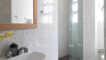 Un baño moderno con lavabo de mármol blanco, espejo con marco de madera y cabina de ducha con paredes de vidrio.
