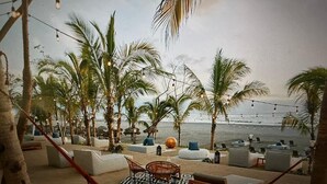 Un salon de plage doté de hamacs, de sièges et de palmiers.